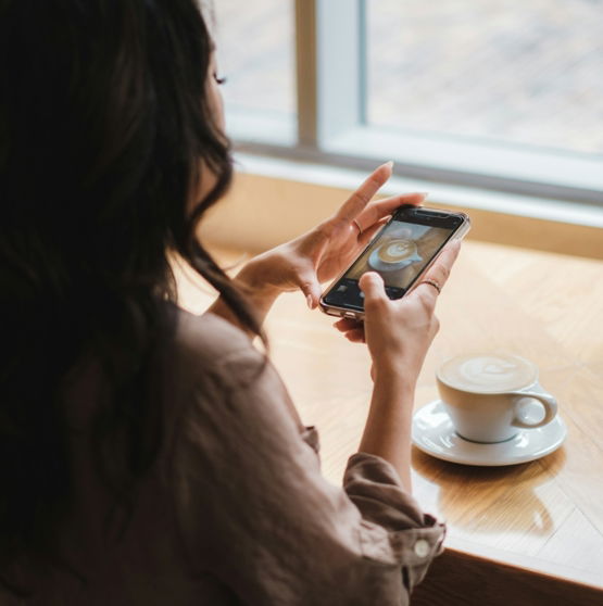 woman in white dress holding black smartphone